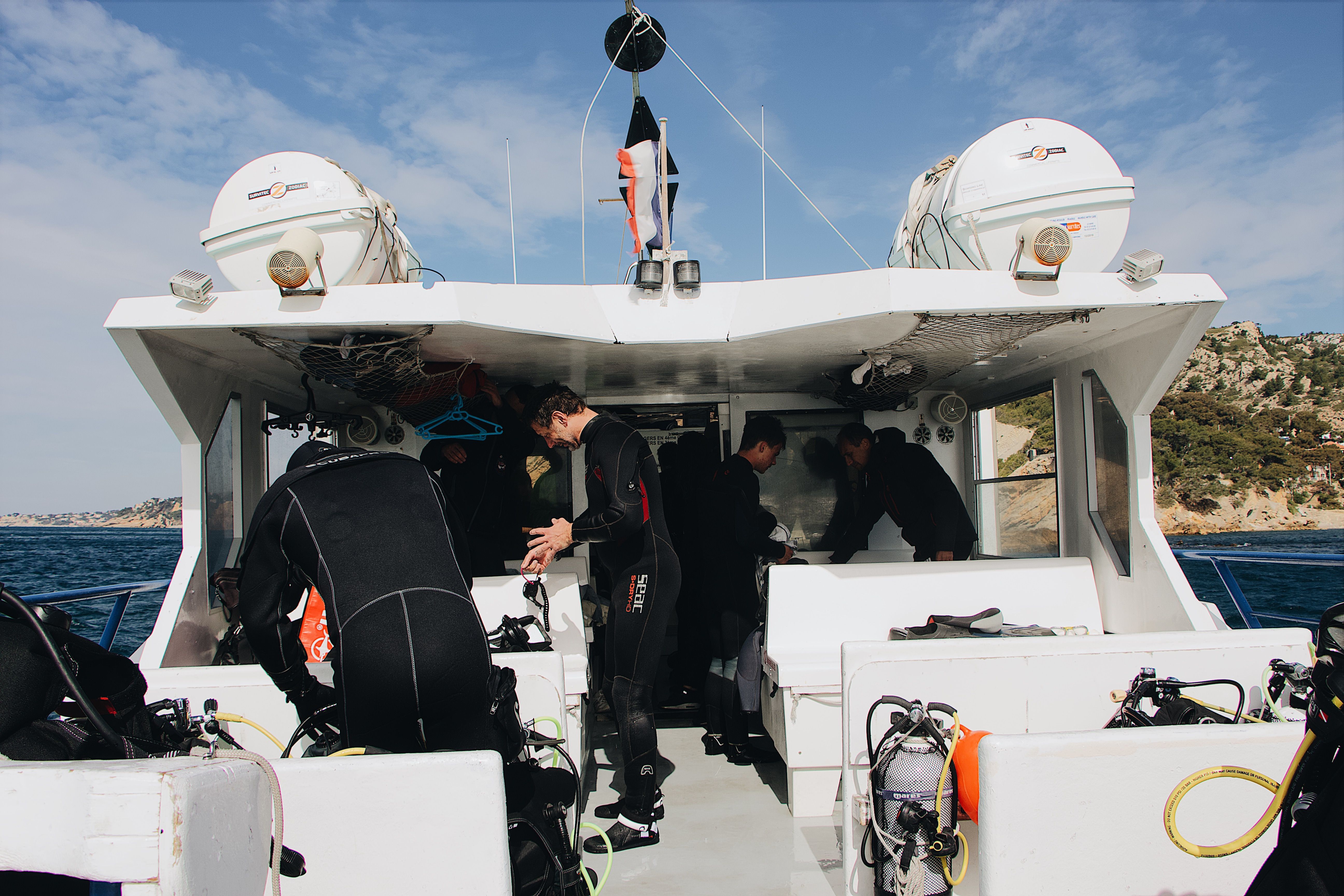 Men in wetsuits on a boat ready to dive. Photo courtesy Maël BALLAND. insta: mael_balland
